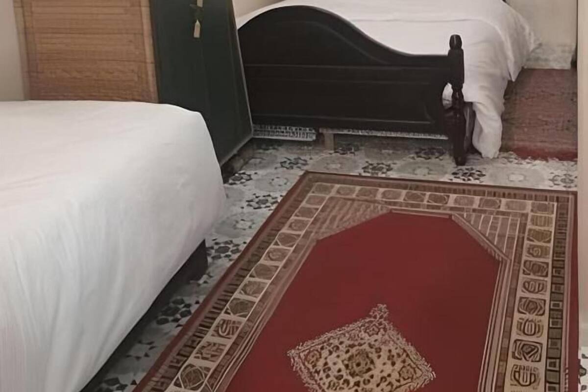 Un dormitorio con una cama individual, una mesita de noche, un aparador y un tapete estampado.
