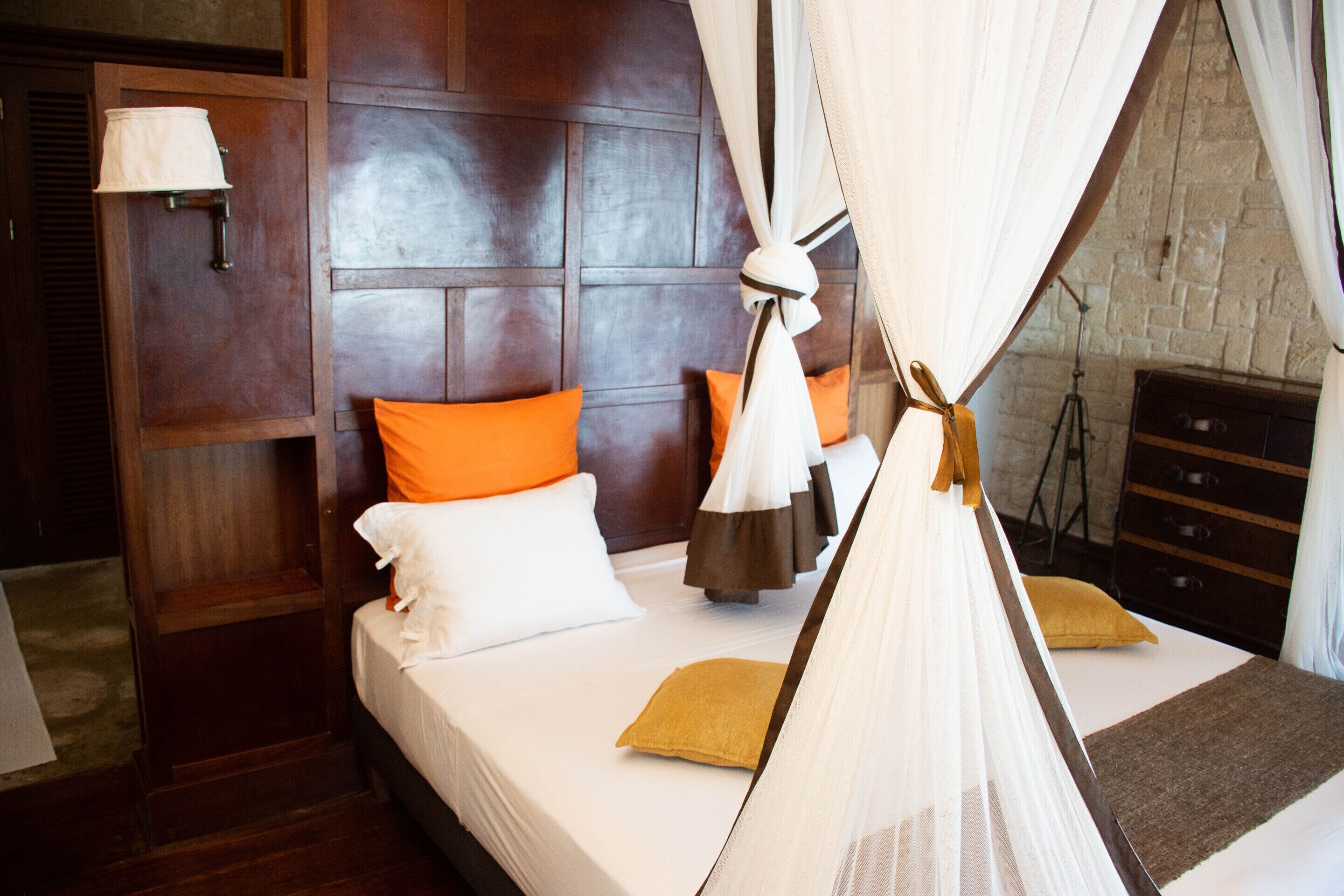 A hotel room with a bed, a nightstand, a lamp, and a wooden headboard.