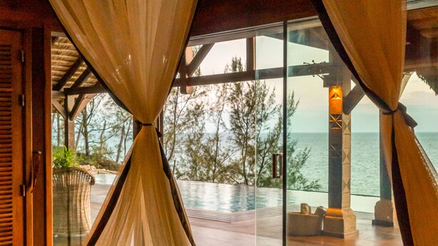 Une chambre avec vue sur la piscine et la mer.