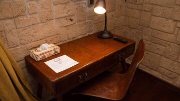 A wooden desk with a lamp, a remote control, a tissue box, and a document on it.