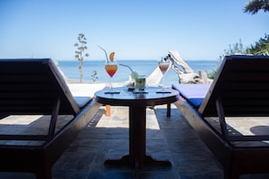 Relax in a serene outdoor setting with a round table and comfortable lounge chairs overlooking a tranquil body of water.