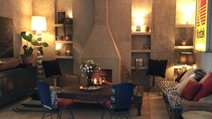 A cozy living room with a fireplace, two armchairs, a sofa, and a coffee table. - Kook Hotel Tarifa (Tarifa)