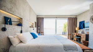 A bedroom with a large bed, a desk, a chair, and a TV. - Kook Hotel Tarifa (Tarifa)