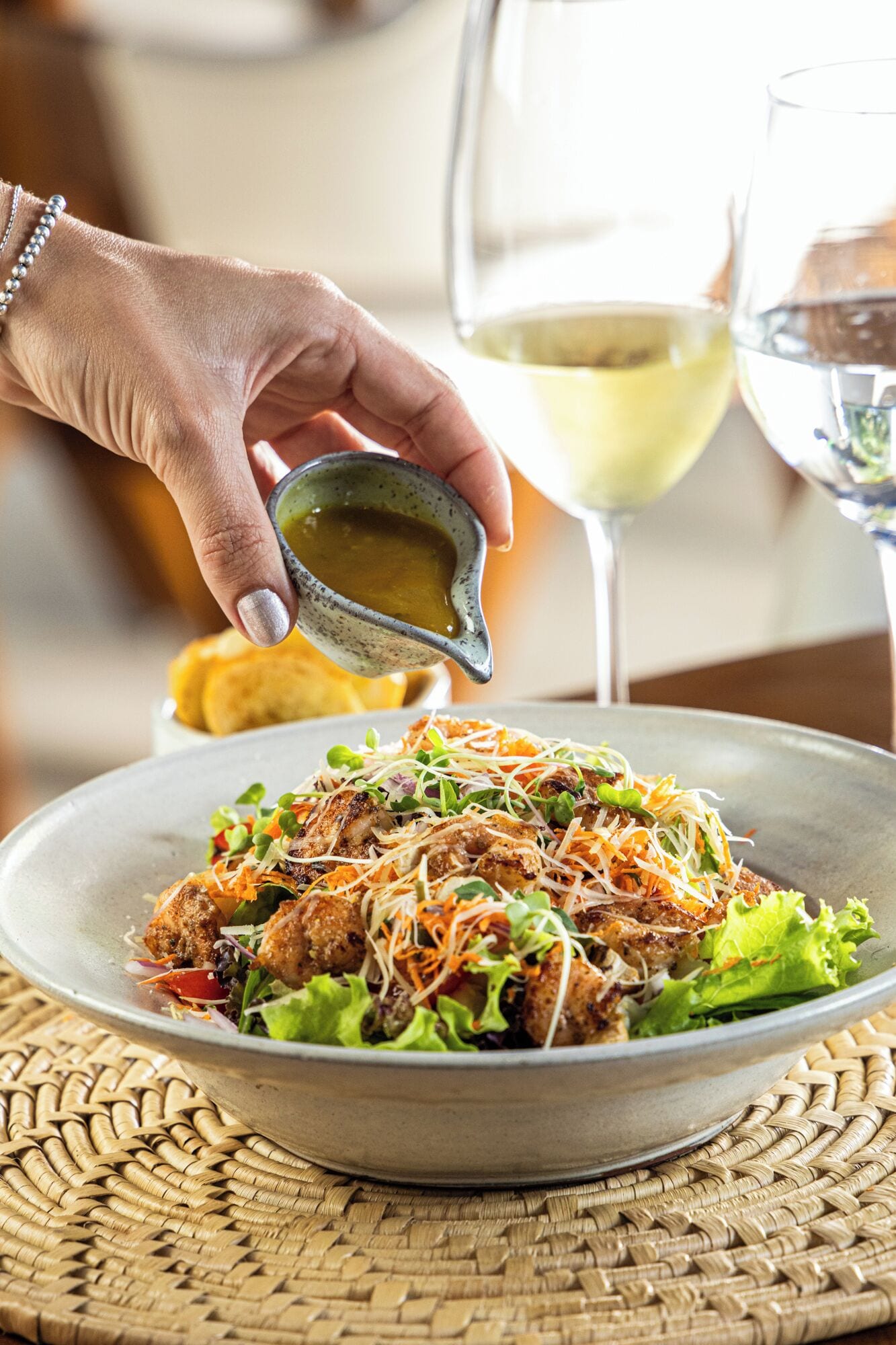 Ensalada con pollo a la parrilla, zanahoria rallada y hojas verdes, rociada con aderezo.