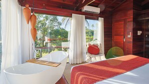 Une salle de bain moderne avec une baignoire sur pieds, un banc en bois et une grande fenêtre donnant sur un paysage verdoyant.