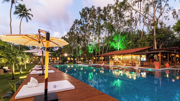 Un espace aménagé au bord de la piscine, avec des chaises longues, des parasols et un bar doté d’une terrasse.