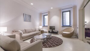 Un salon moderne comprenant un canapé, deux fauteuils, une table basse, un téléviseur et un tapis décoratif.