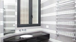 Ein Badezimmer mit einem schwarzen Waschbecken, einem Spiegel mit schwarzem Rahmen und einem Handtuchhalter.