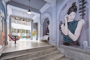 A modern interior with a staircase leading to a reception area, featuring a mural and contemporary furniture.