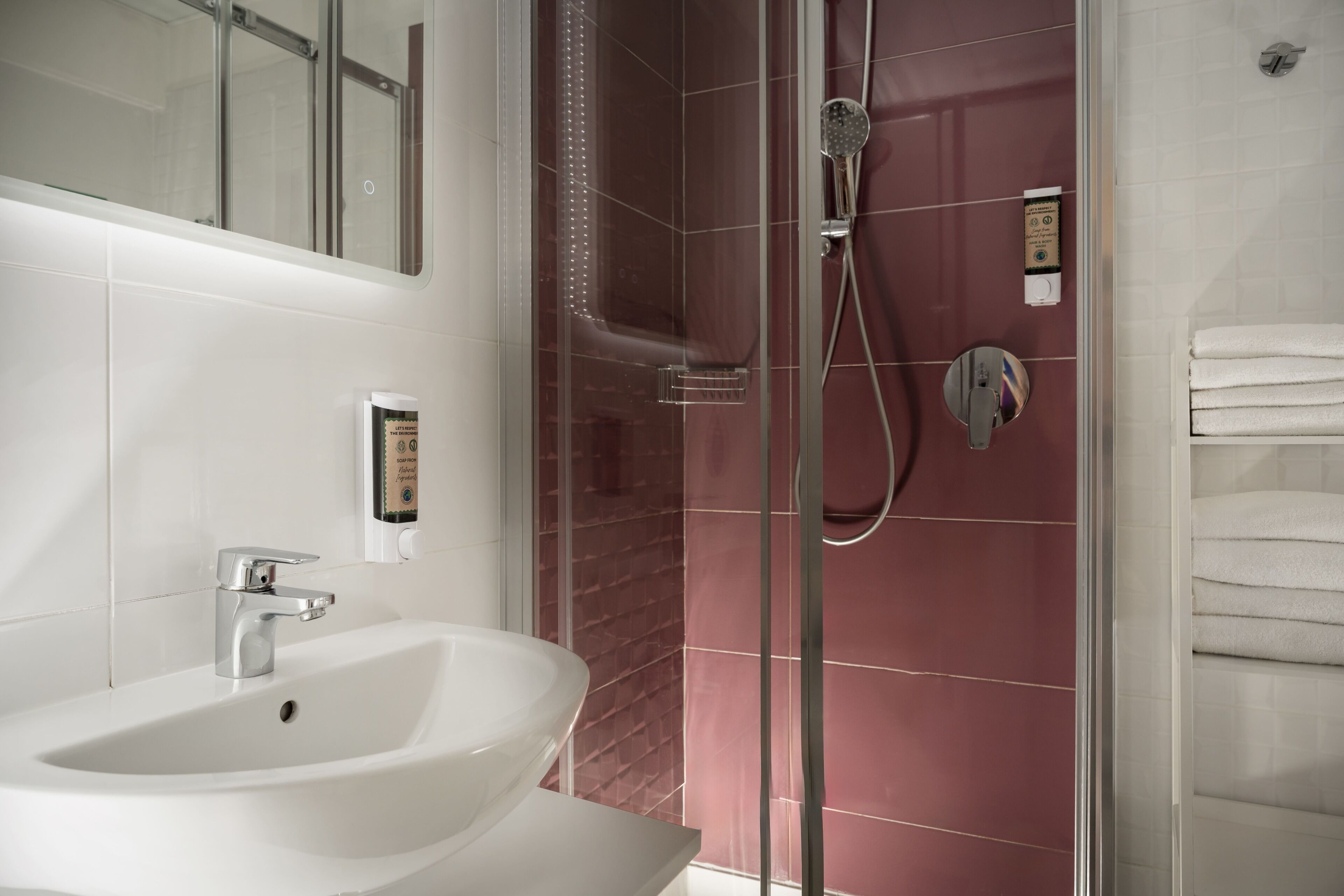 A bathroom with a white sink, a glass-enclosed shower, and a towel rack.