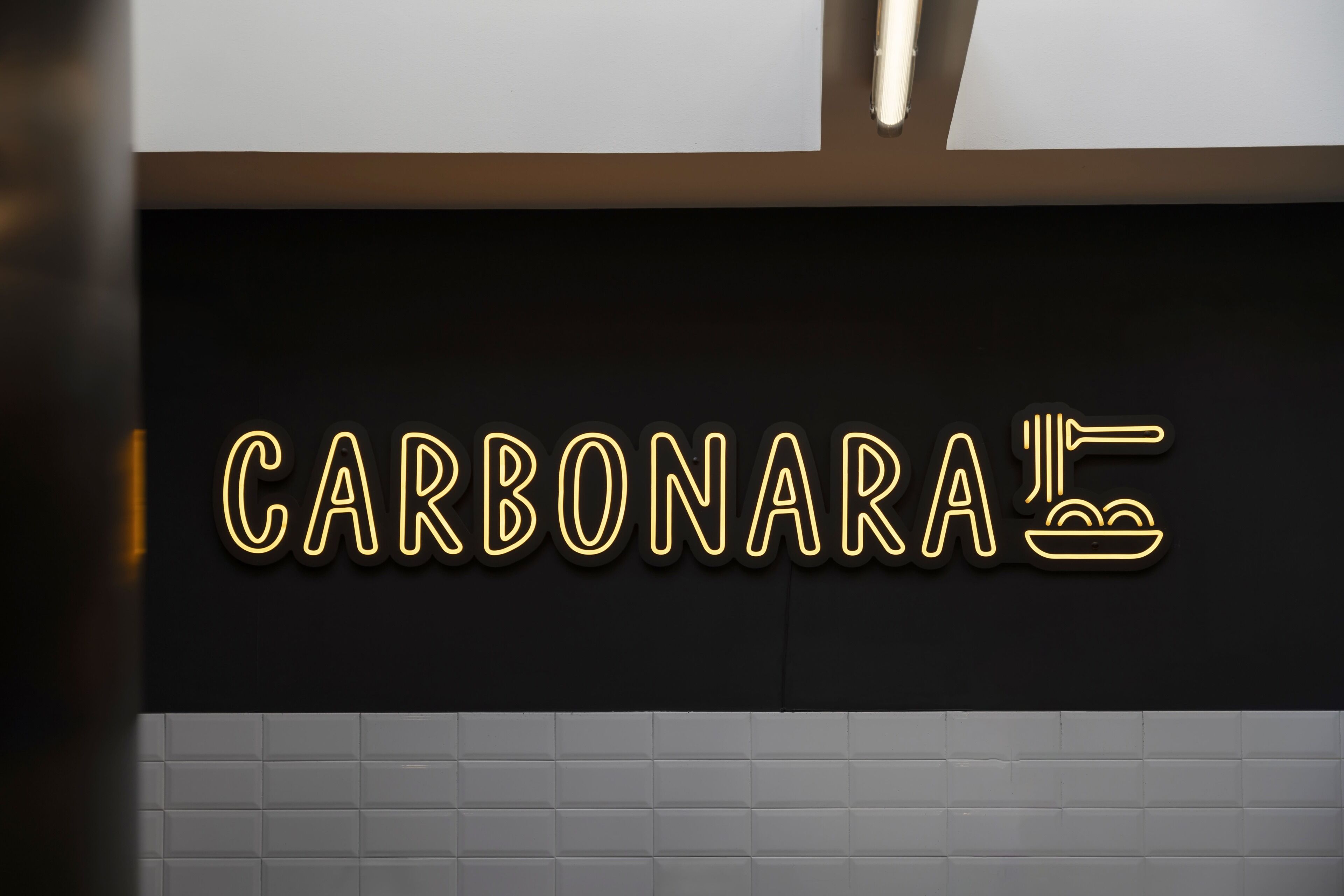 A neon sign with the word 'CARBONARA' and a fork and knife icon.