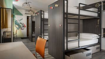 A modern hotel room with bunk beds, a desk, and a chair.