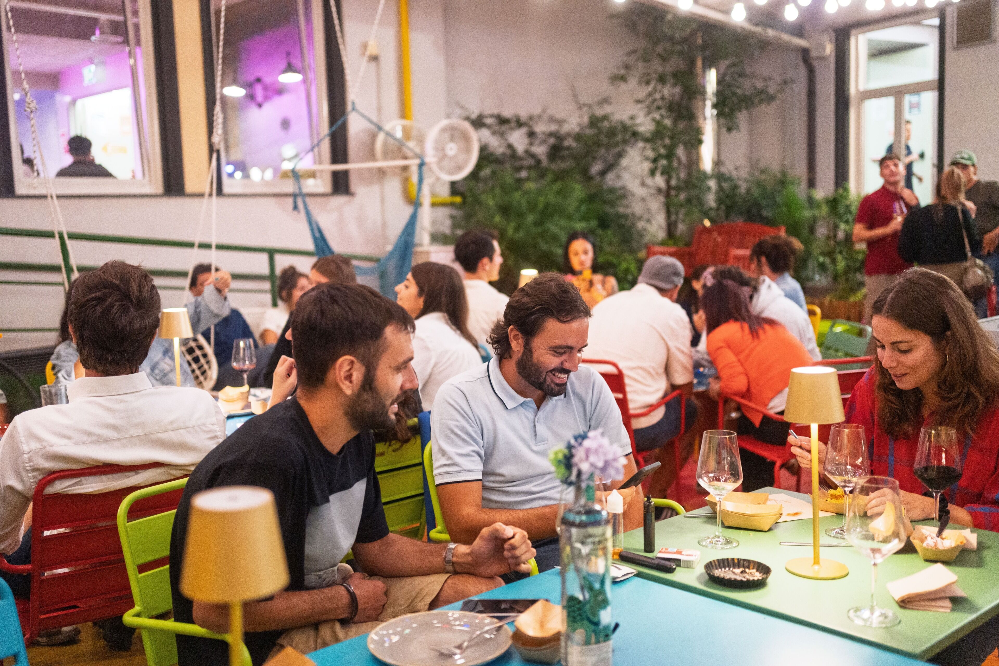 A dining area with tables, chairs, and people seated.