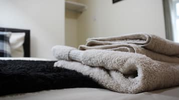 A bed with a folded beige towel and a black pillow.