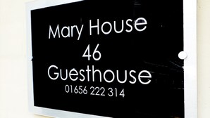A black sign with white text reading "Mary House 46 Guesthouse" and a phone number "01656 222 314".