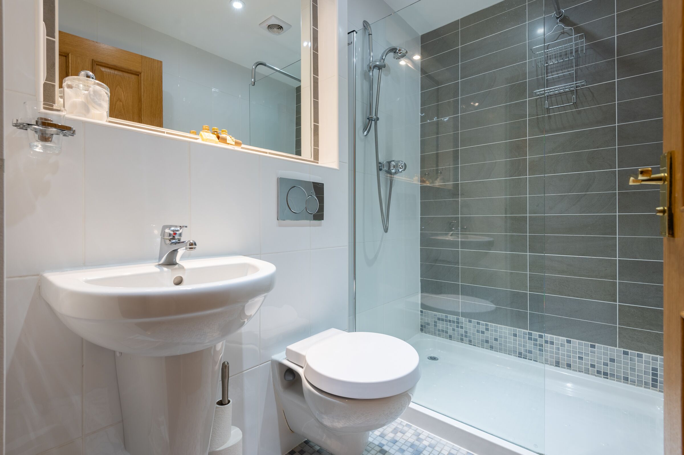 Une salle de bain moderne avec un lavabo blanc, des toilettes et une douche à parois de verre.