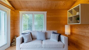 A cozy room with a wooden ceiling, a white sofa with cushions, a small Buddha statue, and a shelf with decorative items. - 138 North Street (St. Andrews)