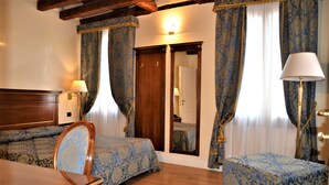 A hotel room with two beds, a wooden dresser, a desk, and a lamp. - B&B Le Marie (Venice)