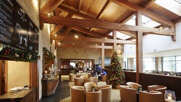 Un hall espacioso con altos techos de madera, un árbol de Navidad y zonas de estar.