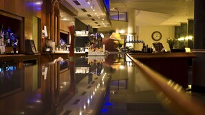 A bar area with a polished floor, a clock on the wall, and a well-lit interior. - The Manor House At Celtic Manor (Newport)