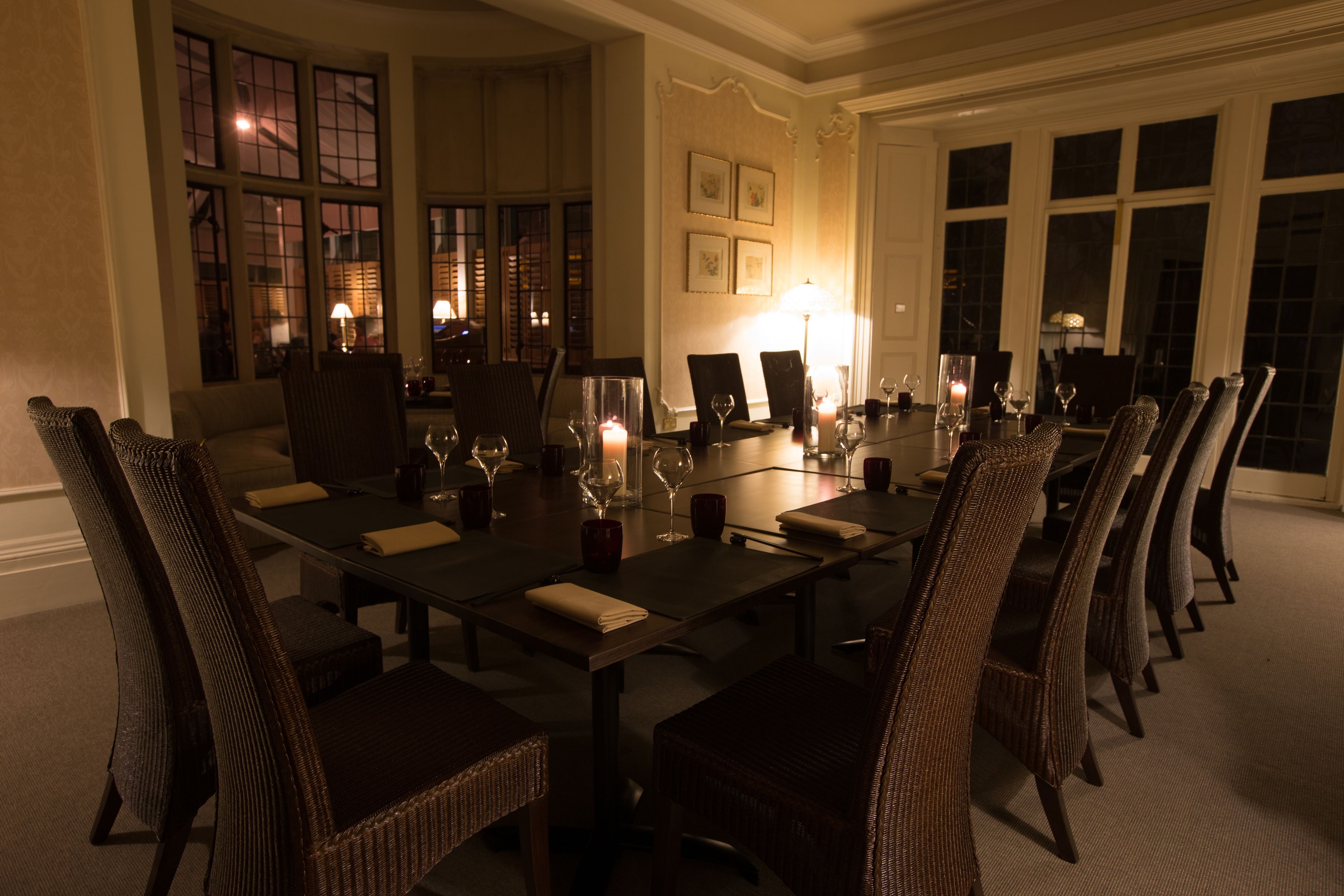 A formal dining room with a long table set for a meal, surrounded by wicker chairs.