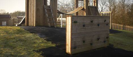 A wooden play structure with a slide and climbing elements.