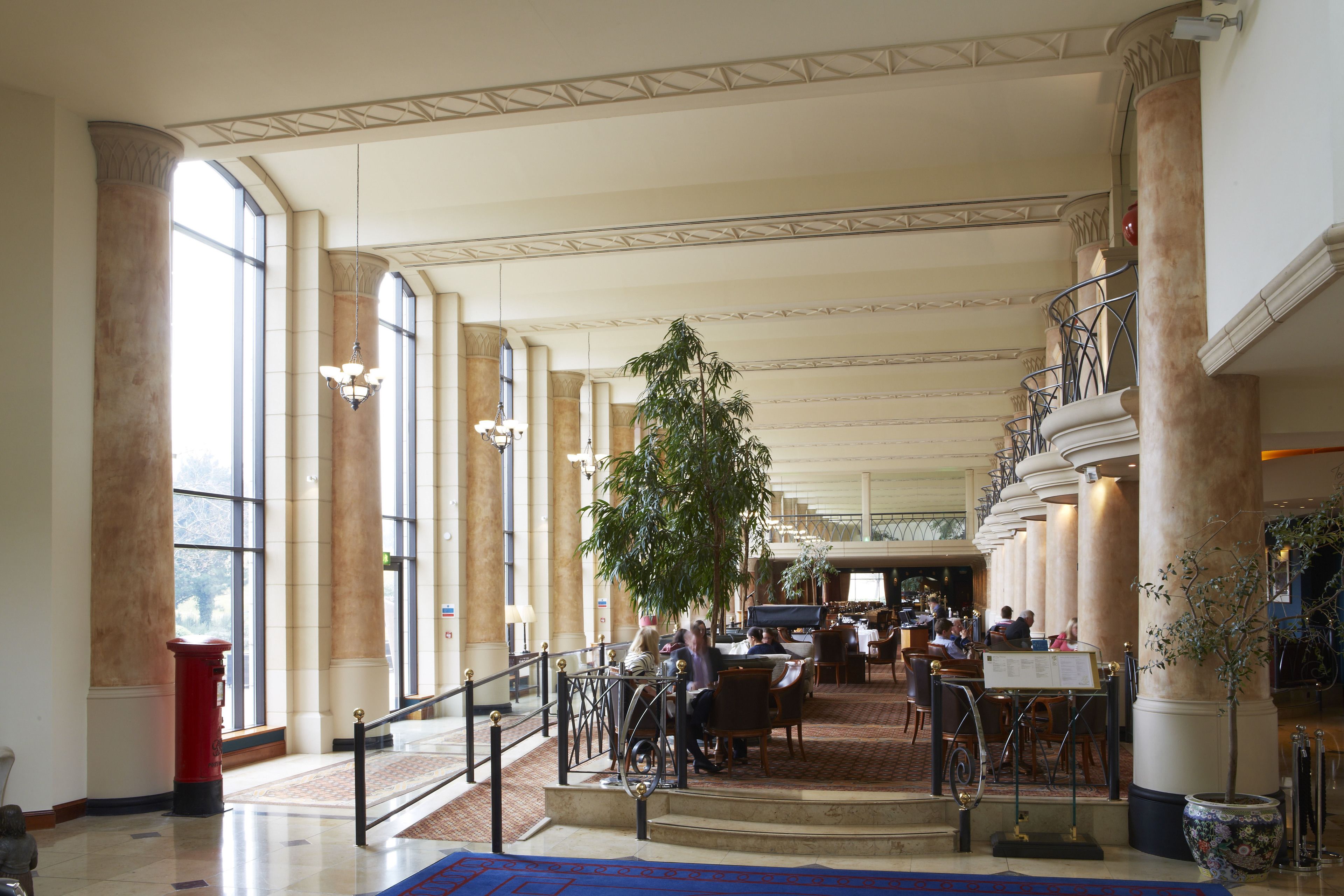 A spacious lobby with high ceilings, large windows, and a central staircase.
