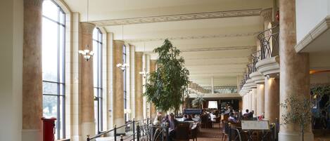 A spacious lobby with high ceilings, large windows, and a central staircase.
