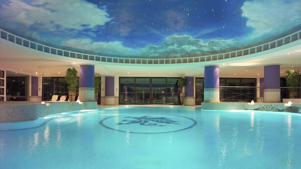 A swimming pool with a starry sky ceiling and a circular logo in the center. - The Manor House At Celtic Manor (Newport)