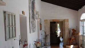 Un pasillo amplio con mobiliario blanco, suelo de baldosas y techo alto.
