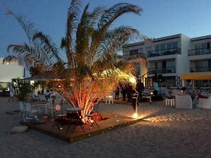 An outdoor seating area with tables and chairs, a fire pit, and palm trees. - Boutique Citadel (Eforie)