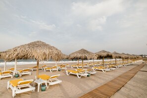 A beach with rows of sun loungers and thatched umbrellas. - Boutique Citadel (Eforie)