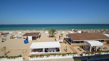 Un complejo turístico frente a la playa con varias cabañas, piscina y vista despejada del océano.