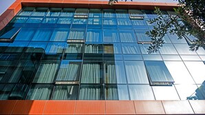 A modern building with large glass windows and a red and white facade. - MySun Hotel (Izmir)