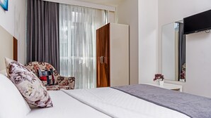 A hotel room with a bed, a chair, a wardrobe, a desk, and a mirror. - MySun Hotel (Izmir)