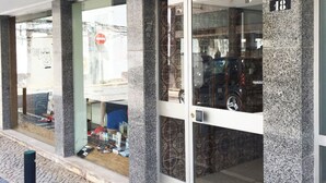 A building facade with large glass doors, a stone pillar with the number 18, and a cobblestone ground. - Lemon Tree Apartments (Faro)