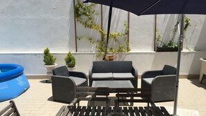 A patio with wicker furniture, a blue inflatable pool, and potted plants. - Lemon Tree Apartments (Faro)