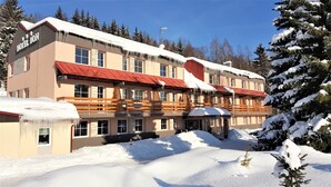 Un hotel con tejado rojo, múltiples ventanas y fachada cubierta de nieve.