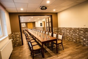 Uma sala de conferências com uma mesa comprida e cadeiras, um projetor e paredes de pedra.