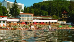 A waterfront hotel with multiple dining areas, a boat dock, and a forested hill in the background. - Ensana Bradet (Sovata)