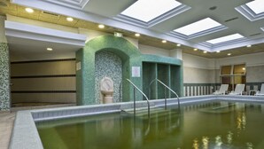 An indoor swimming pool with clear water, a tiled floor, and a green mosaic wall. - Ensana Bradet (Sovata)