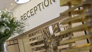 A reception area with a sign that reads "RECEPTION" and a decorative wall with a sun-like pattern. - Ensana Bradet (Sovata)