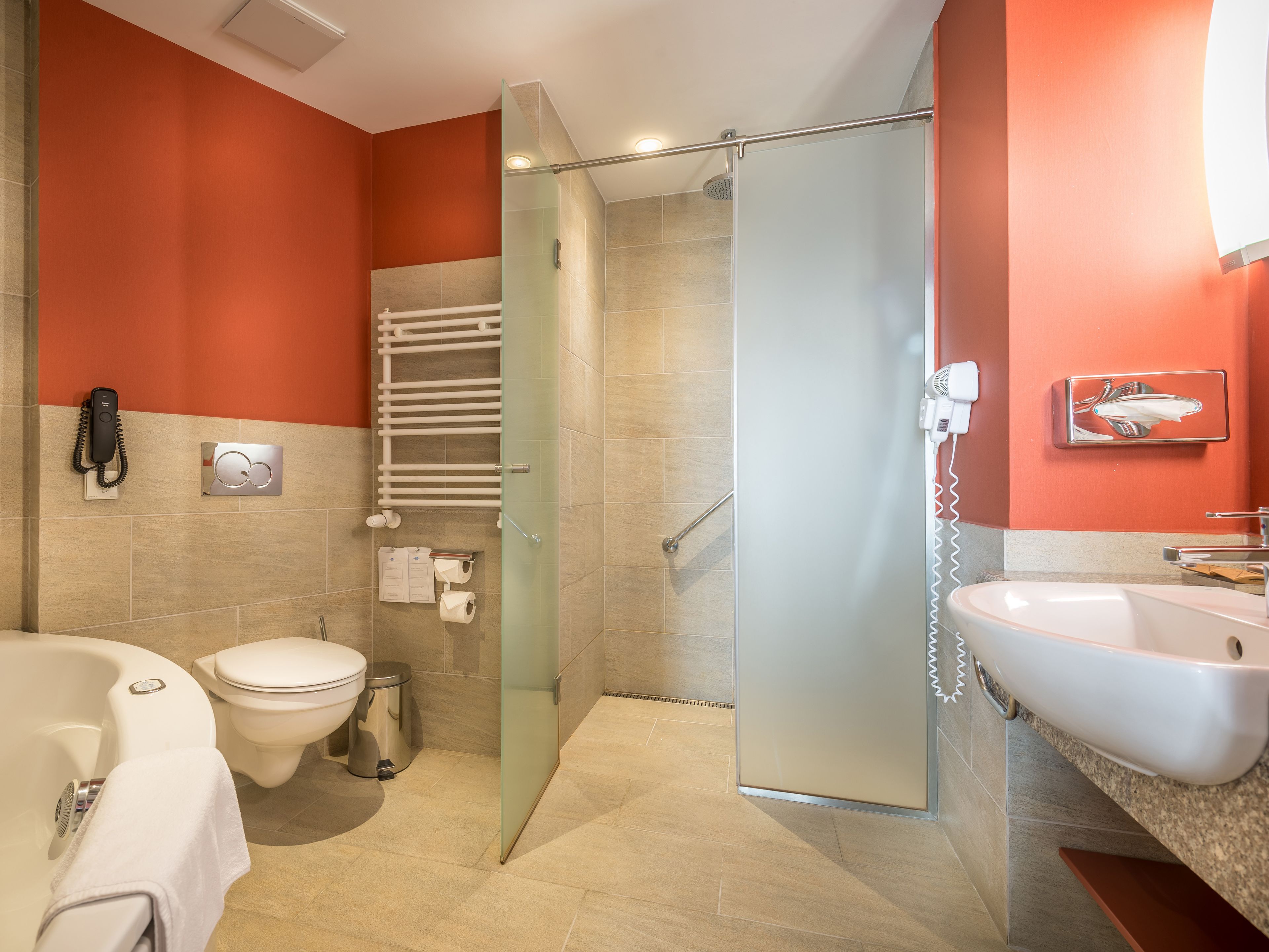 A modern bathroom with a glass shower door, a white sink, a toilet, and a bathtub.
