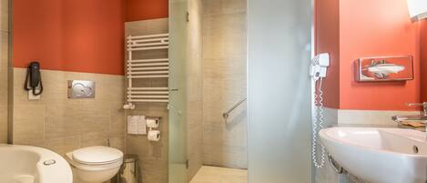 Un baño moderno con mampara de vidrio, un lavamanos blanco, un inodoro y una bañera.