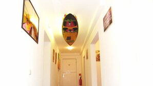 A hallway with wooden flooring, white walls, and various framed artworks.