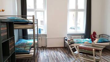 Ein Zimmer mit Etagenbetten, Holzboden, Heizkörper und einem Fenster mit Vorhängen.