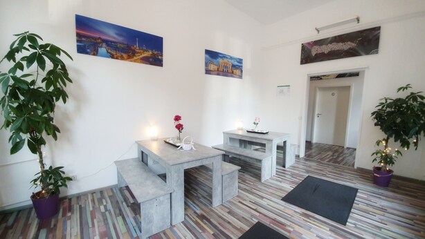 A room with a modern design, featuring a multi-colored wooden floor, a small table with a vase of flowers, and two benches.