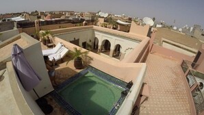 Un área de piscina en la azotea con una piscina pequeña, sillas de descanso y una planta en maceta.