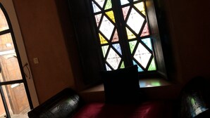 Una habitación con ventana que presenta un diseño geométrico, una colcha roja y dos sillones a juego.