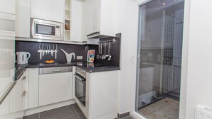 A compact kitchen with white cabinets, a microwave, a dishwasher, and a stove. - Vienna Hotspot - Rathaus (Vienna)